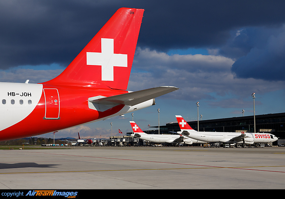 Tail of Holiday Jet A319 HB-JOH and 2 Swiss A340-300 parked in the background Airbus A319-111