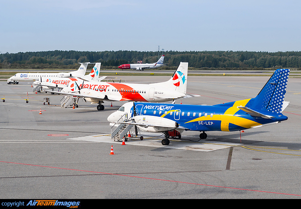 Line-up of several NextJet Saab aircraft, a BMI ERJ and a Norwegian 737 in the background. Saab 340A